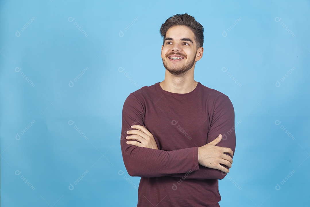 Homem sorridente de braços cruzados sobre um fundo isolado azul.