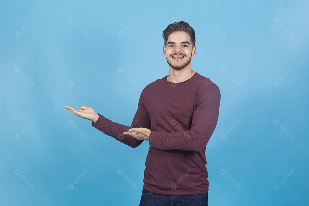 Homem sorridente apontando para o lado sobre um fundo isolado azul.