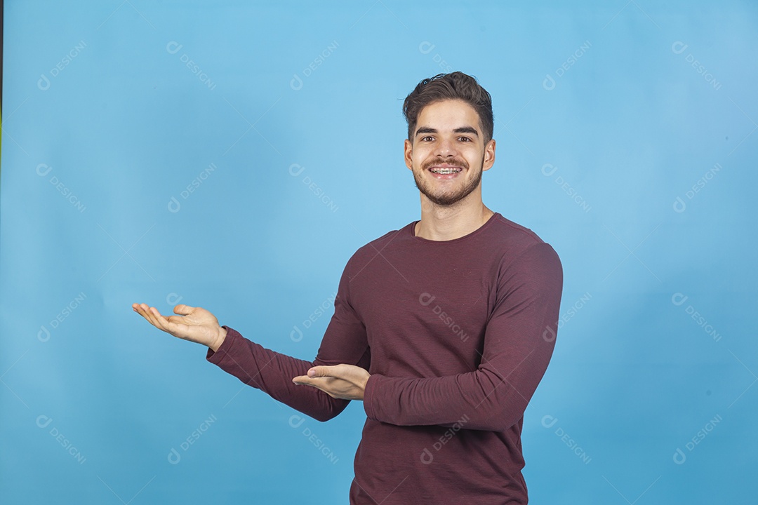 Homem sorridente apontando para o lado sobre um fundo isolado azul.