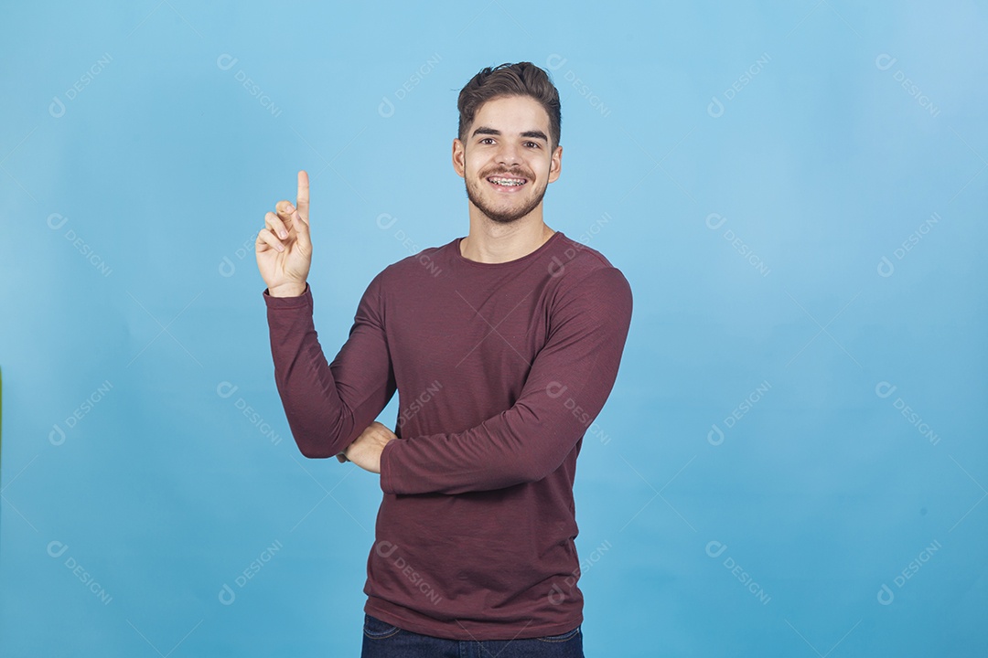 Homem sorridente apontando para cima sobre um fundo isolado azul.