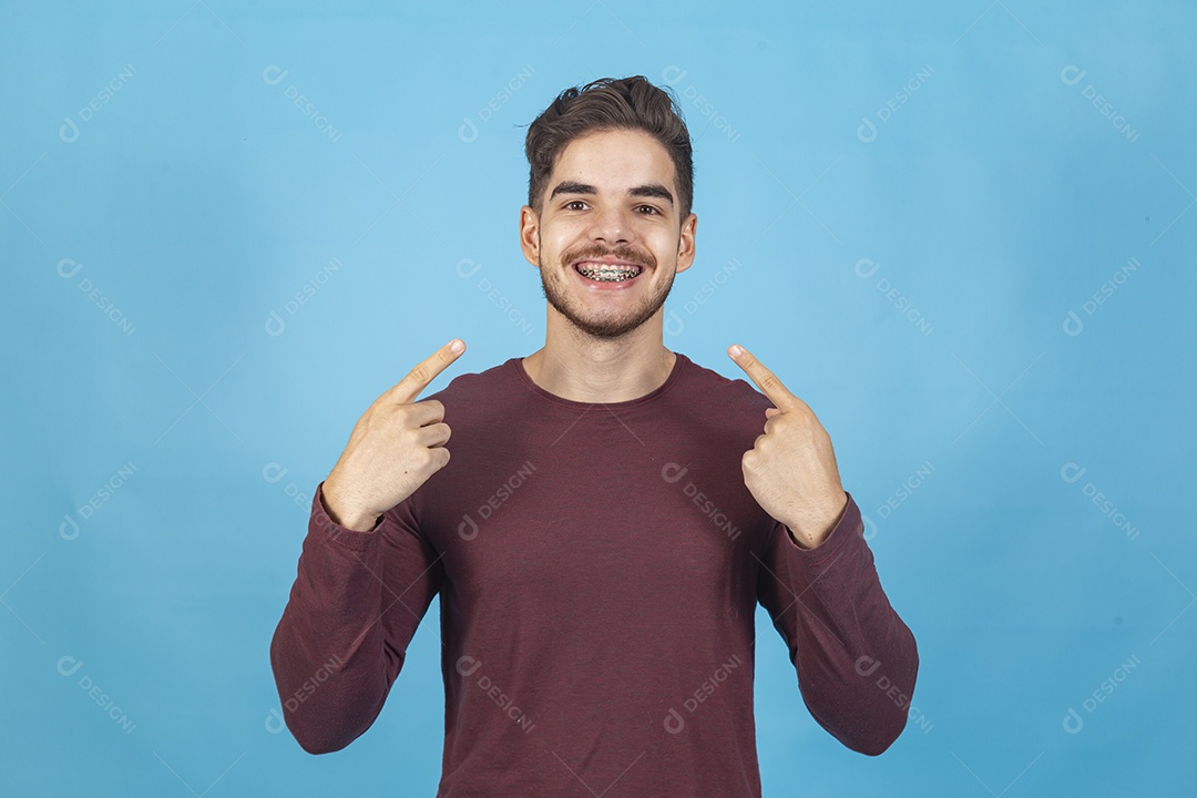 Homem sorridente apontando para si mesmo  sobre um fundo isolado azul.