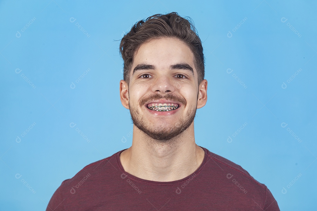Homem jovem sorridente sobre um fundo isolado azul.