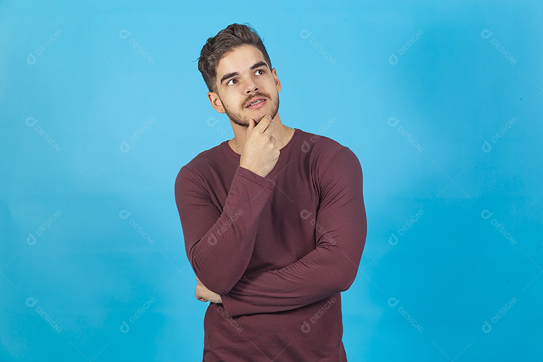 Homem de camisa manga longa sobre fundo isolado azul.
