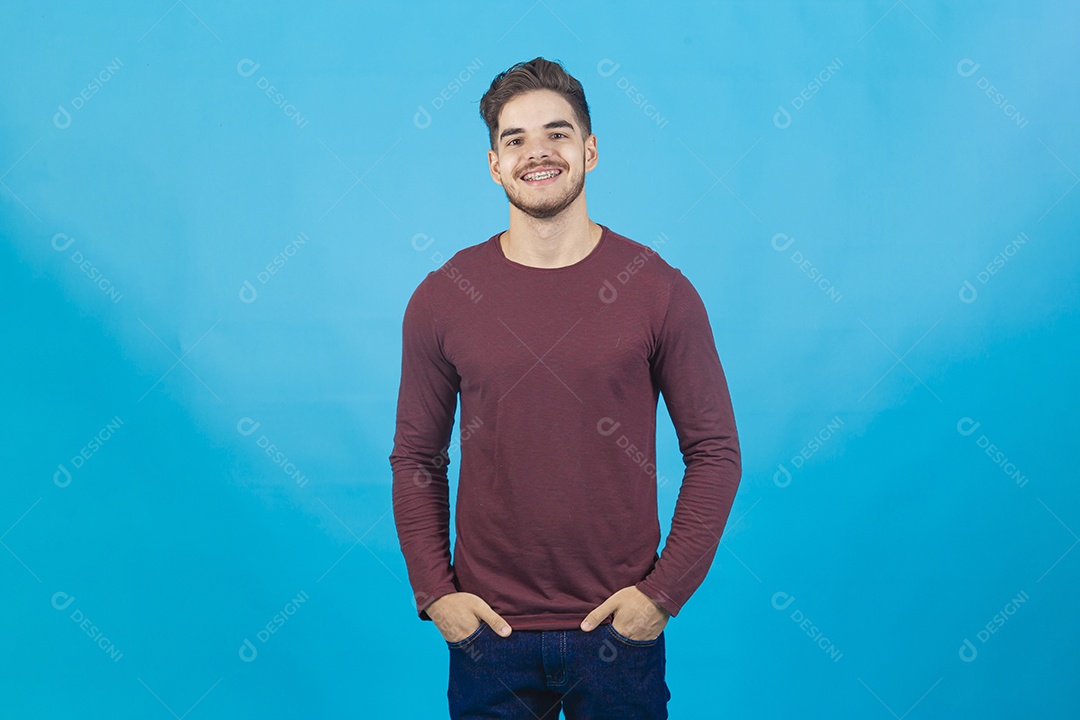 Homem jovem com as mão no bolso sobre fundo isolado azul
