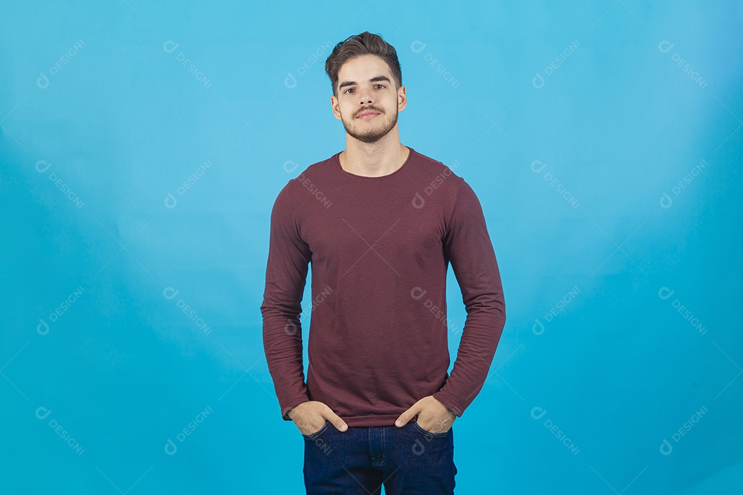 Homem jovem com as mão no bolso sobre fundo isolado azul