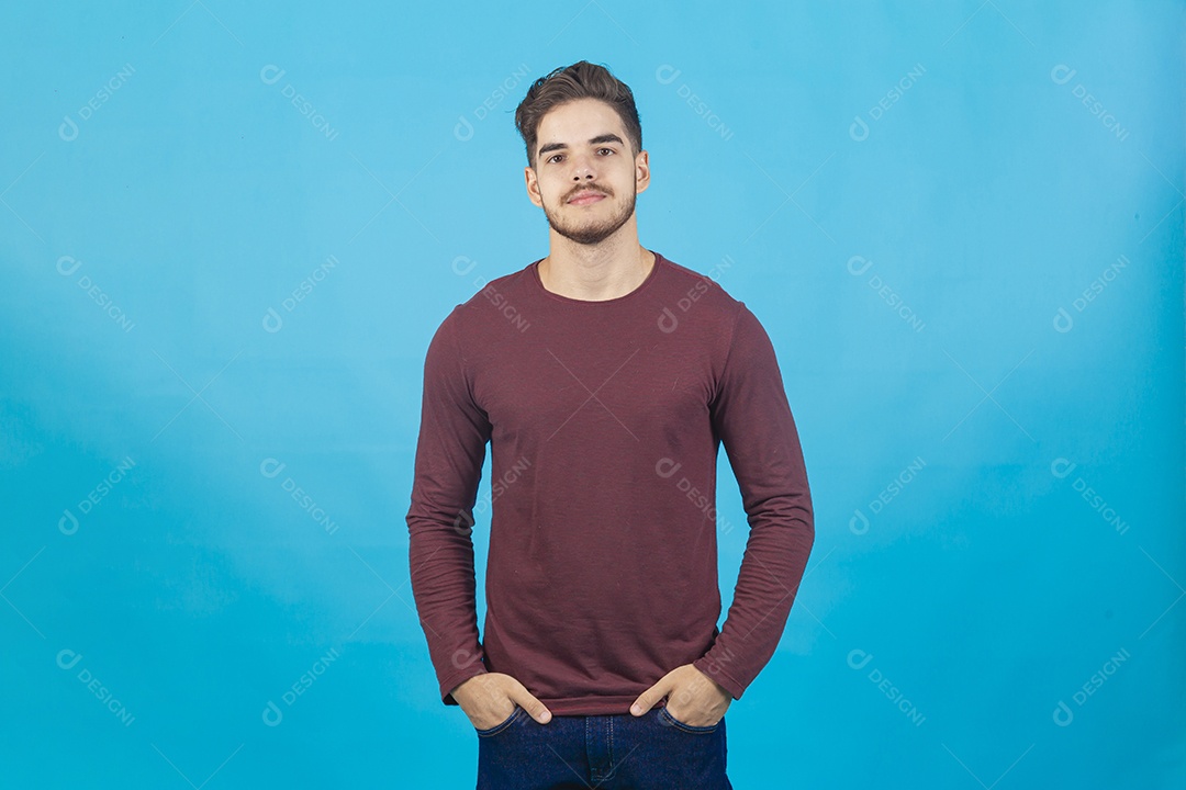Homem jovem com as mão no bolso sobre fundo isolado azul
