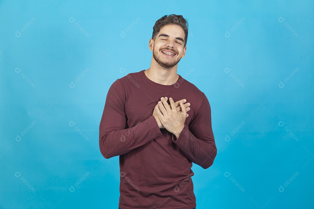 Homem sorridente com as mãos sobre o peito.