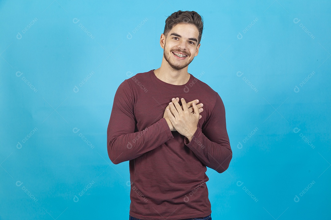 Homem sorridente com as mãos sobre o peito.