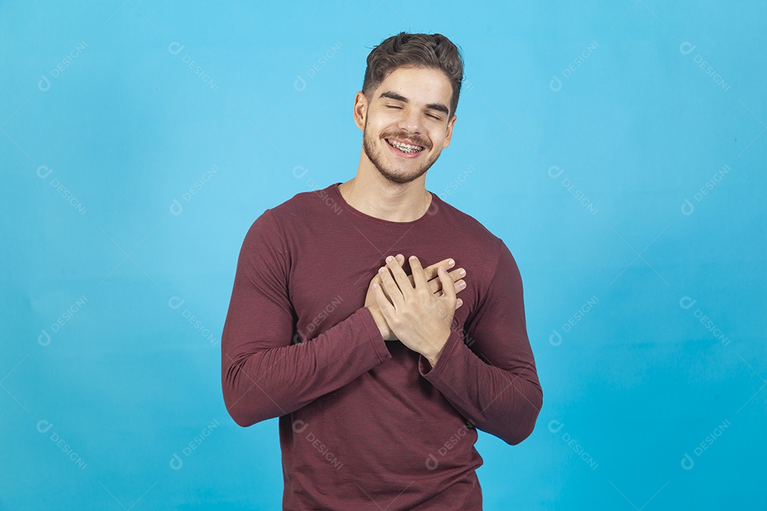 Homem sorridente com as mãos sobre o peito.