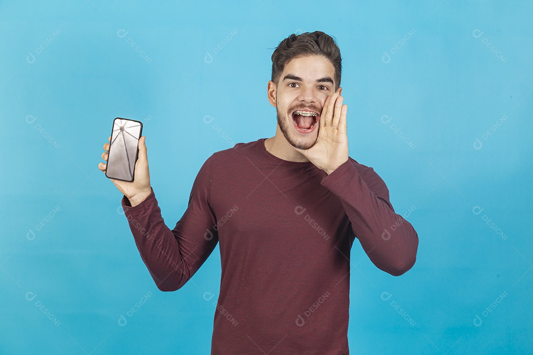 Homem sorridente segurando celular sobre um fundo isolado azul.