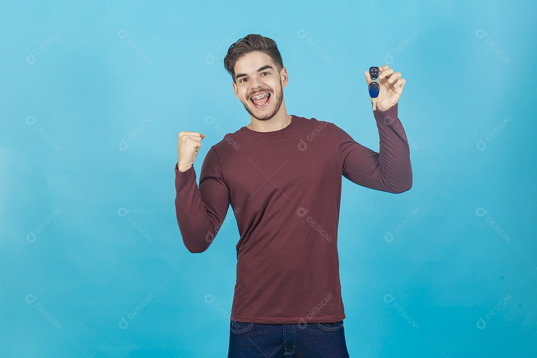 Homem comemorando segurando chave sobre um fundo isolado azul.