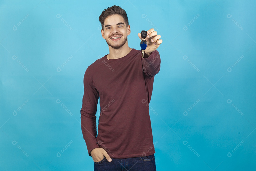 Homem sorridente segurando chave sobre um fundo isolado azul.