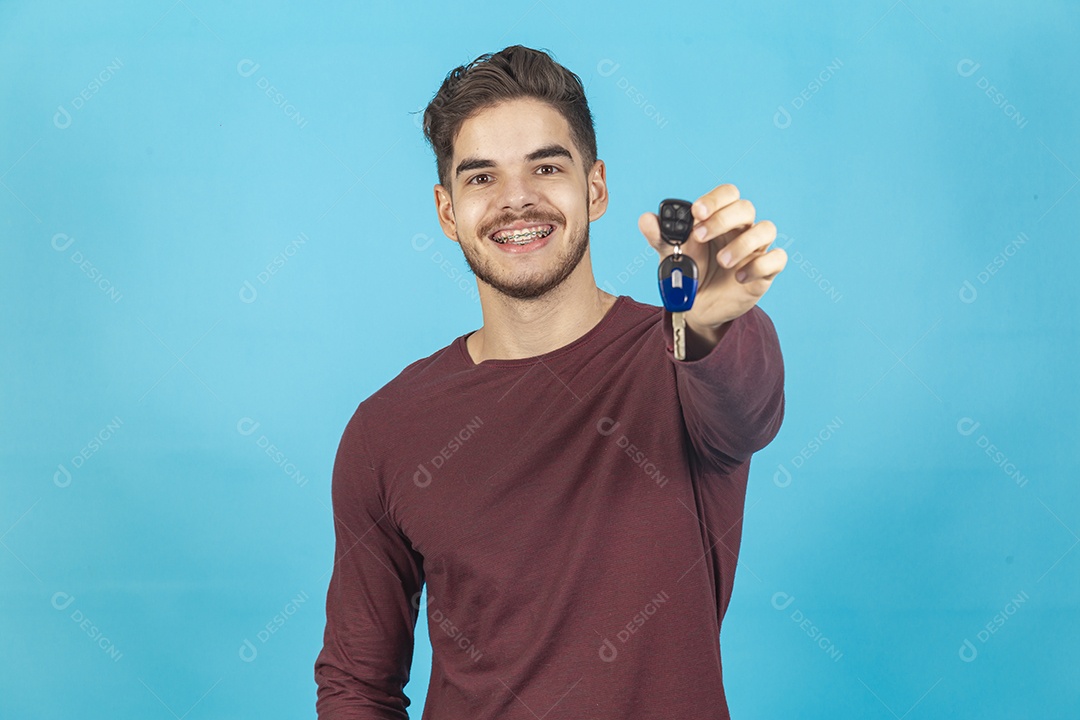 Homem comemorando segurando chave sobre um fundo isolado azul.
