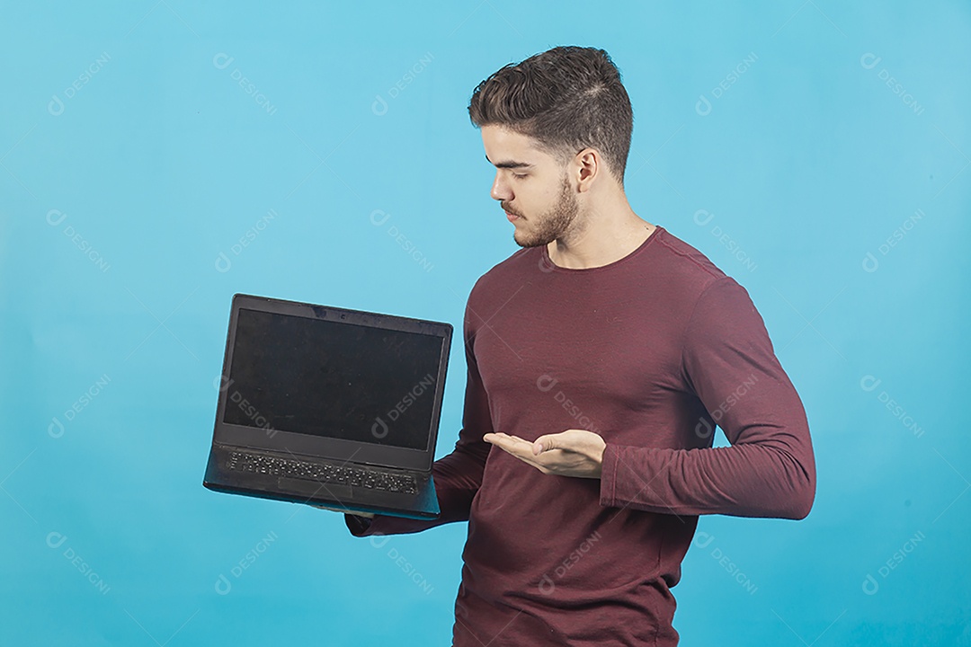 Homem jovem segurando notebook sobre fundo isolado azul.