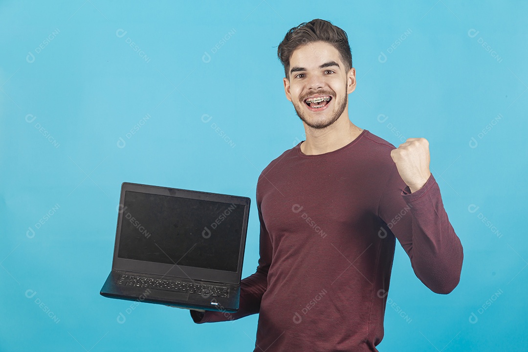 Homem jovem segurando notebook sobre fundo isolado azul.
