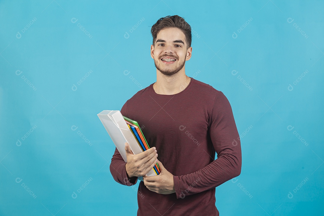 Homem sorridente segurando livro sobre um fundo isolado azul.
