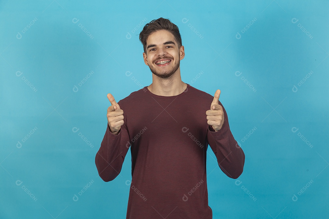 Homem fazendo sinal positivo sobre fundo isolado azul.