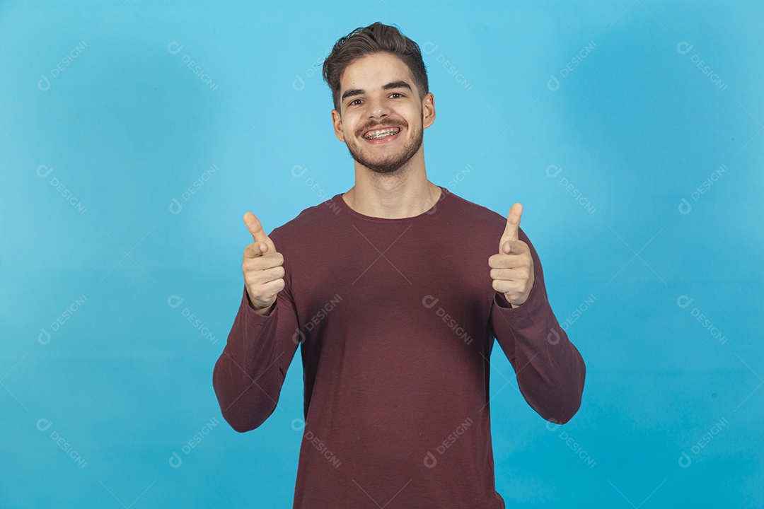 Homem fazendo sinal positivo sobre fundo isolado azul.