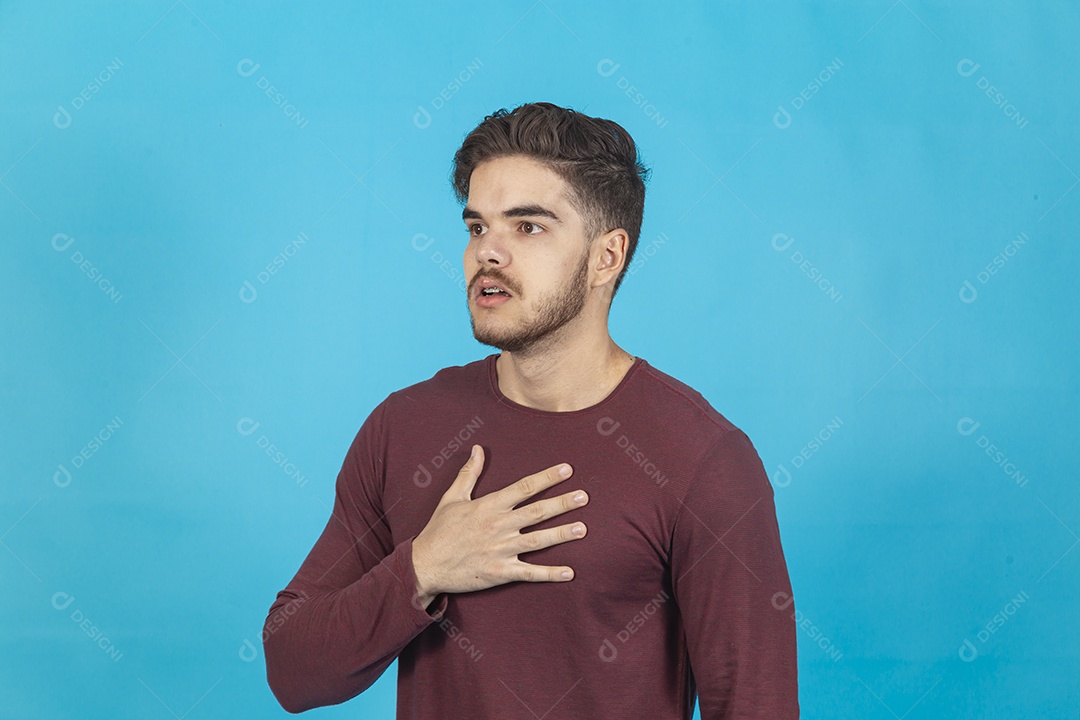 Homem com a mão no peito sobre fundo isolado azul.