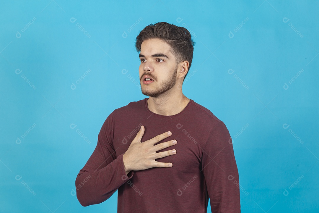 Homem com a mão no peito sobre fundo isolado azul.