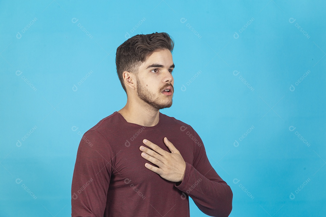Homem com a mão no peito sobre fundo isolado azul.