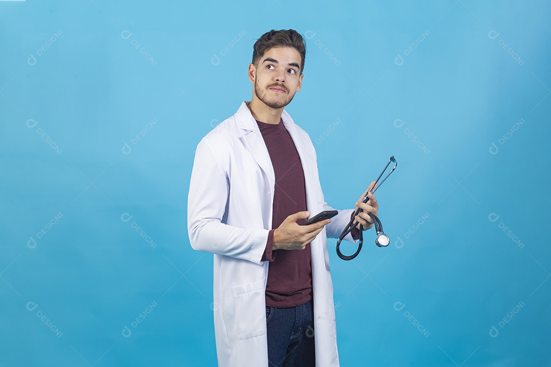 Homem jovem usando jaleco segurando celular e estetoscópio.