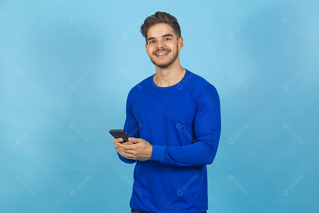 Homem de camisa manga longa segurando celular.