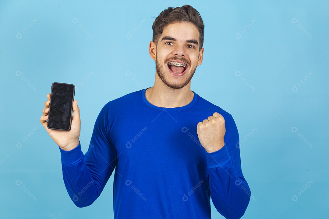 Homem sorridente segurando celular sobre um fundo isolado azul.