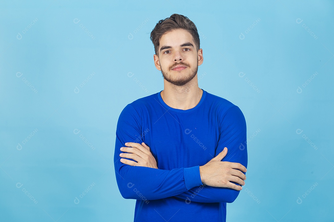 Homem de braços cruzados sobre um fundo isolado azul.
