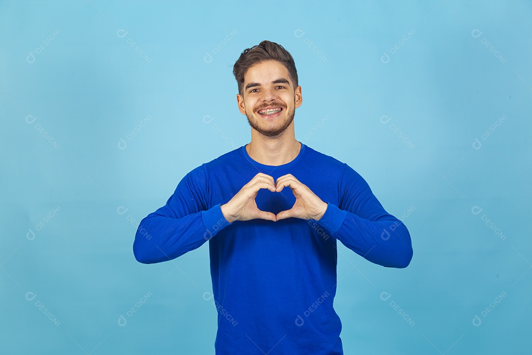 Homem fazendo símbolo do coração vestido de camiseta manga longa azul.