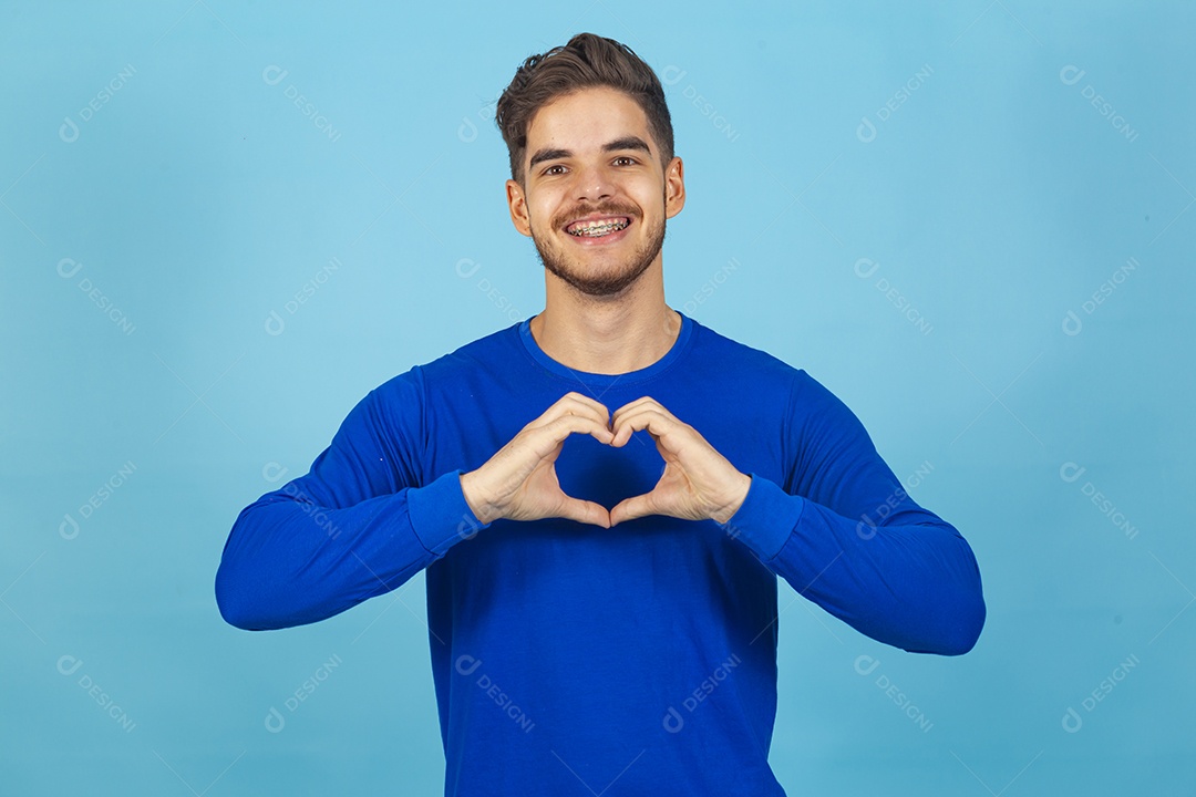 Homem fazendo símbolo do coração vestido de camiseta manga longa azul.