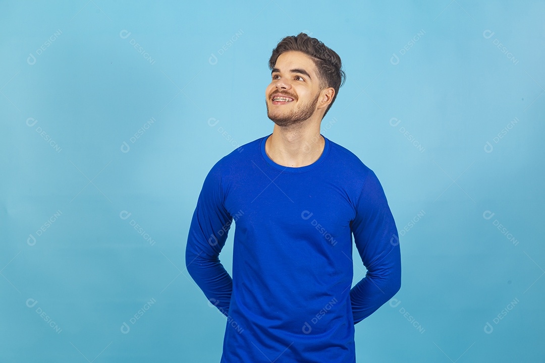 Homem sorridente vestido de camiseta manga longa azul.