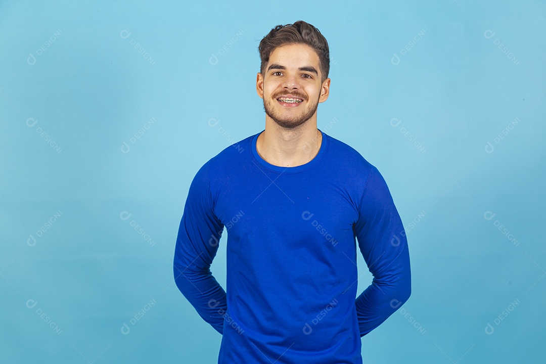 Homem de mãos para trás vestido de camiseta manga longa azul.