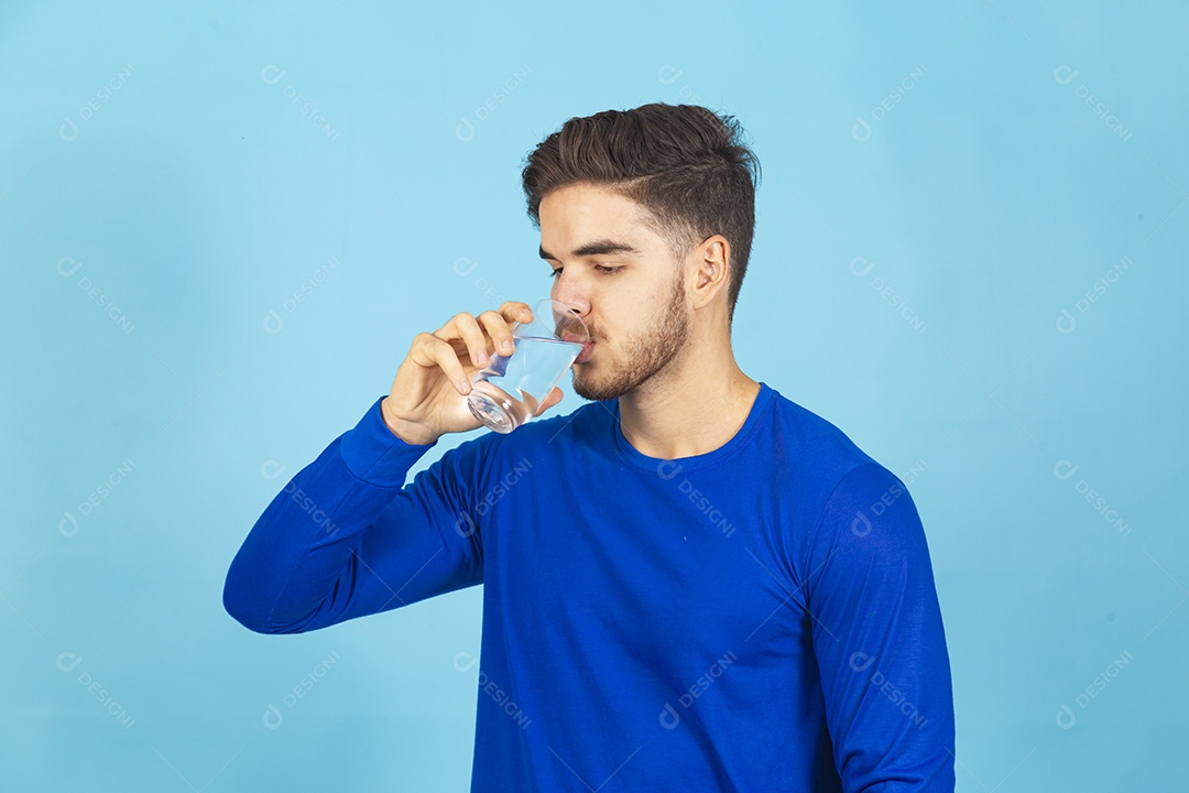 Homem bebendo água sobre um fundo isolado azul.