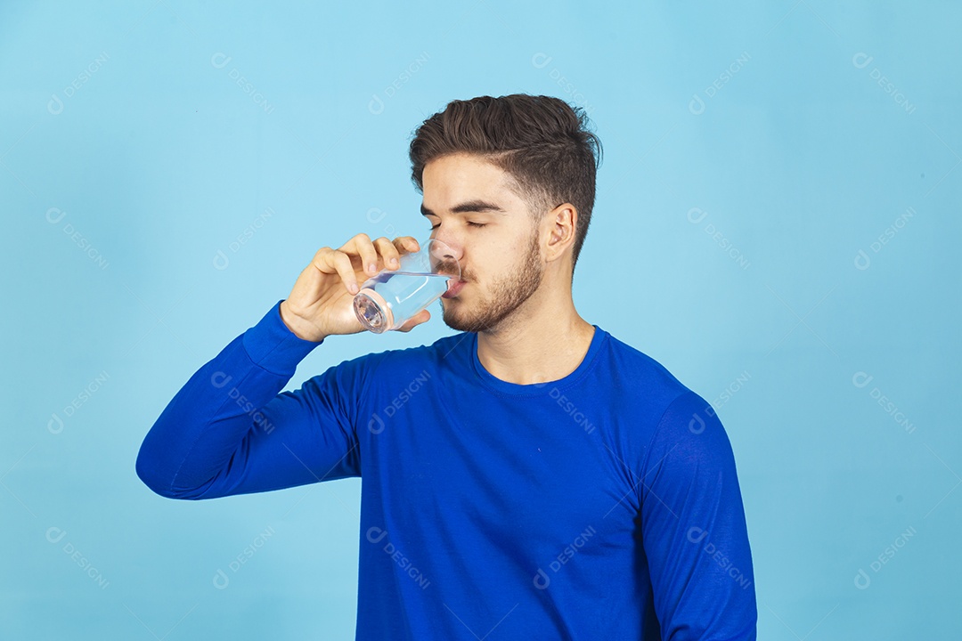 Homem bebendo água sobre um fundo isolado azul.