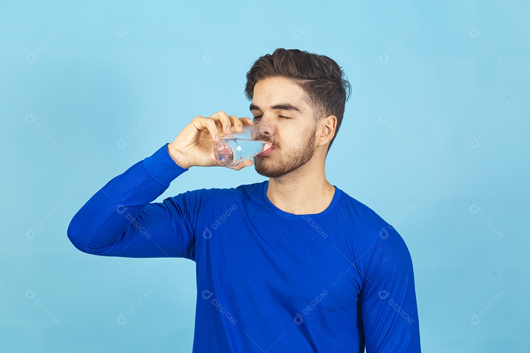 Homem bebendo água sobre um fundo isolado azul.