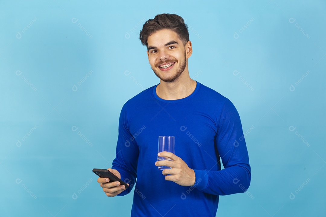 Homem sorridente segurando celular sobre um fundo isolado azul.