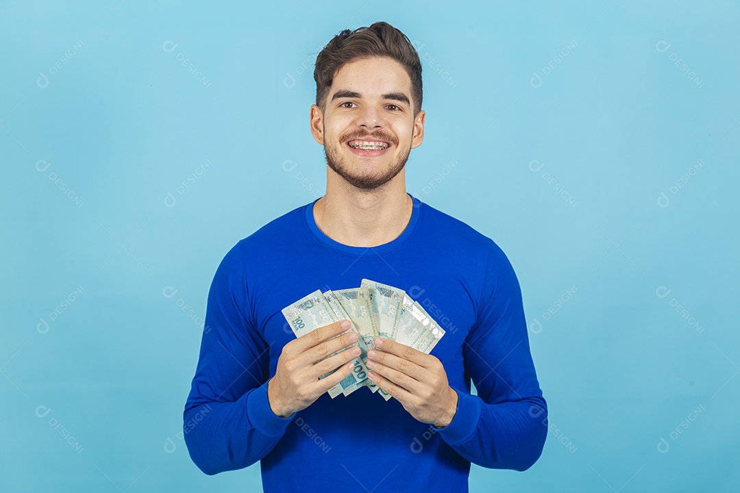 Homem jovem e feliz com cédulas em mãos.