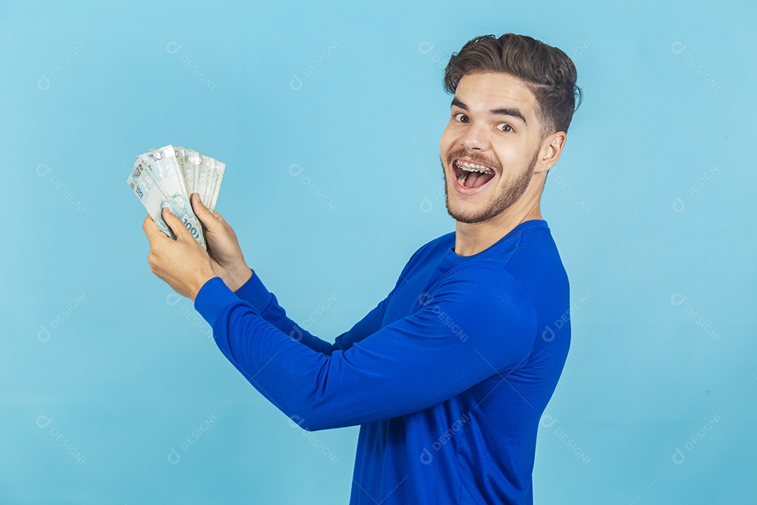 Homem jovem e feliz com cédulas em mãos.