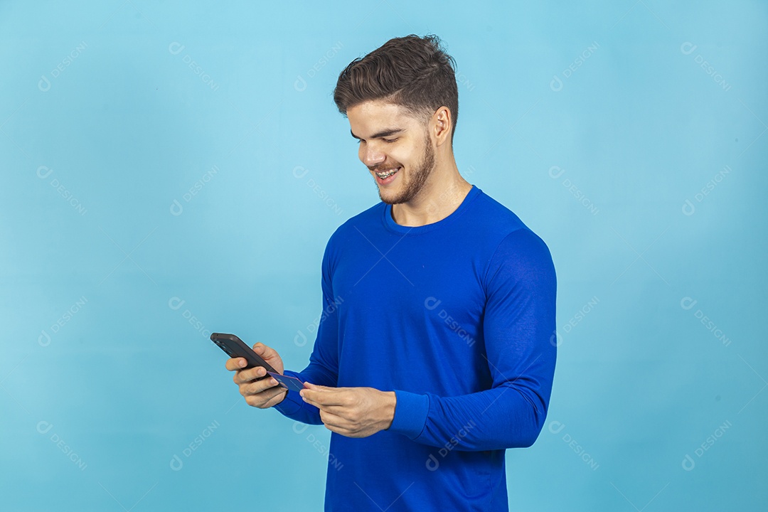 Homem segurando celular sobre um fundo isolado azul.