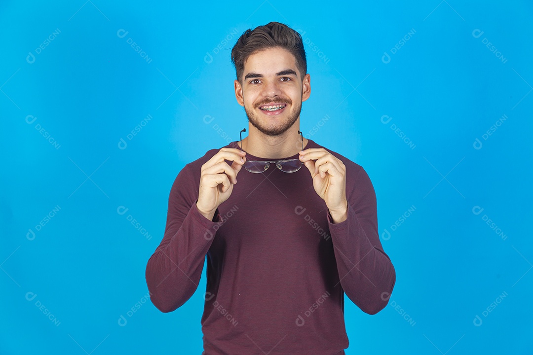 Homem sorridente usando óculos sobre um fundo isolado azul.
