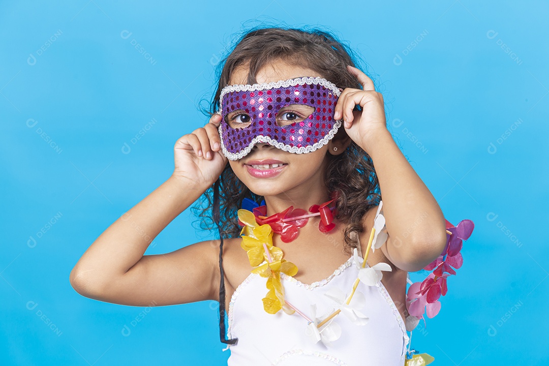 Linda menina com máscara carnavalescas sobre fundo isolado azul.