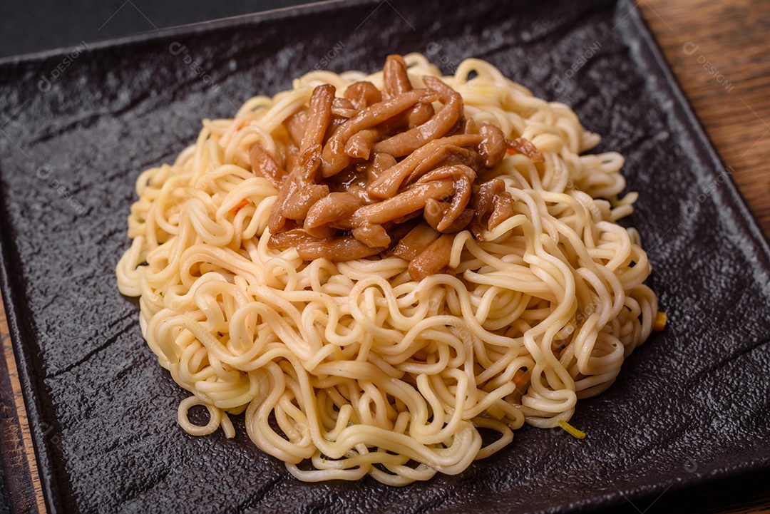 Delicioso prato de cozinha asiática com macarrão de arroz, pimentão, cogumelos e especiarias sobre fundo escuro de concreto