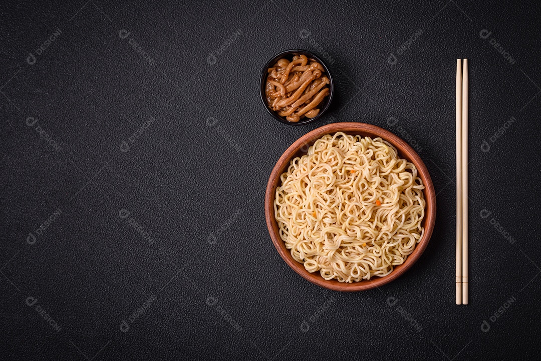 Delicioso prato de cozinha asiática com macarrão de arroz, pimentão, cogumelos e especiarias sobre fundo escuro de concreto
