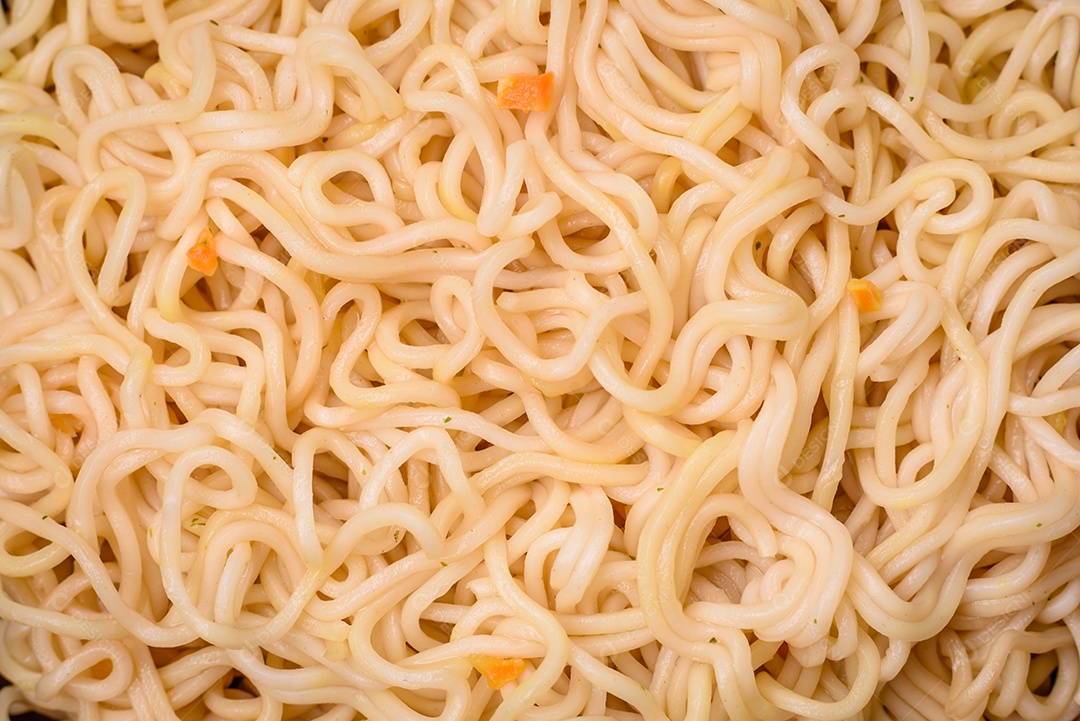 Delicioso prato de cozinha asiática com macarrão de arroz, pimentão, cogumelos e especiarias sobre fundo escuro de concreto