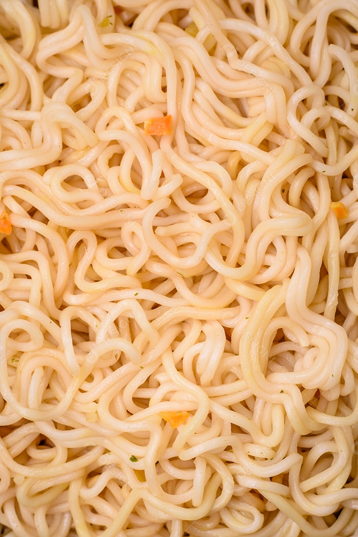 Delicioso prato de cozinha asiática com macarrão de arroz, pimentão, cogumelos e especiarias sobre fundo escuro de concreto