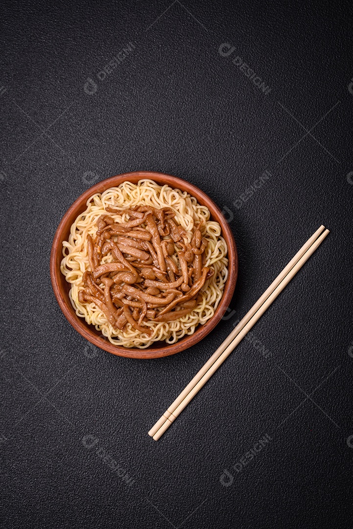 Delicioso prato de cozinha asiática com macarrão de arroz, pimentão, cogumelos e especiarias sobre fundo escuro de concreto
