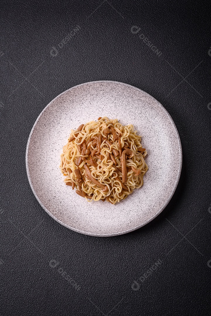 Delicioso prato de cozinha asiática com macarrão de arroz, pimentão, cogumelos e especiarias sobre fundo escuro de concreto