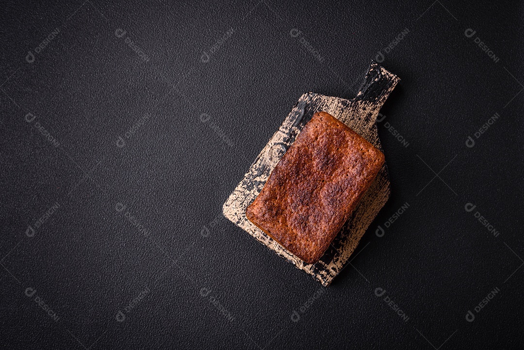 Delicioso pão integral crocante fresco com sementes e grãos sobre um fundo escuro de concreto