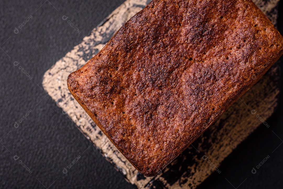 Delicioso pão integral crocante fresco com sementes e grãos sobre um fundo escuro de concreto